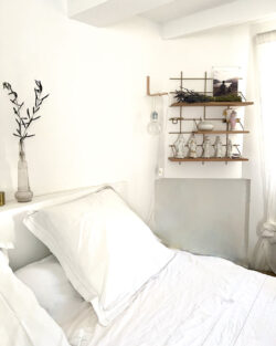 Chambre weiß épurée mit Regale Gassien Paris aus Holz und Messing, statuundtes und lavande séchée.