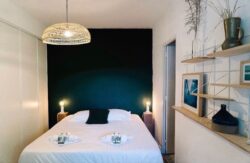 Chambre cosy mit Regal Gassien Paris aus Holz, mur bleu nuit und décoration skandinavisch épurée.