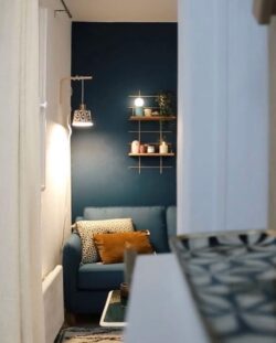 Wohnzimmer cosy bleu canard mit Regale Holz und Messing Gassien Paris, Atmosphäre chaleureuse tamisée.