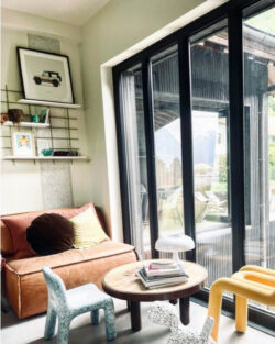 Wohnzimmer cosy mit Regal Gassien Paris noire, canapé cuir und touches colorées enfant.