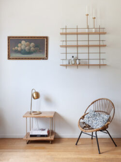 Wohnzimmer cosy Gassien Paris mit Regal Messing aus Holz, fauteuil rotin und tableau floral vintage.